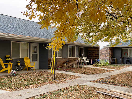 A yellow chair is in front of a house.