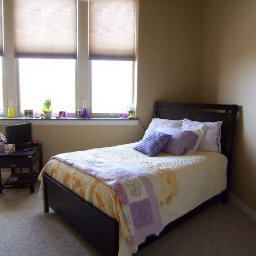 A bedroom with a bed, a desk, and a window.