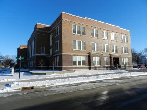 A large brick building with a snow-covered ground in front.