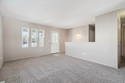 A spacious room with carpeted floor and a large window.