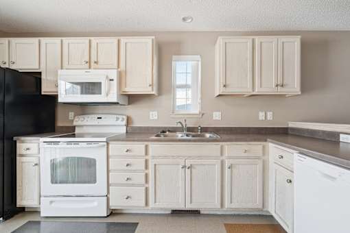 A kitchen with white appliances and cabinets.