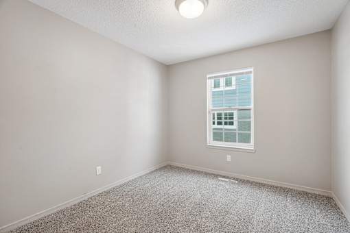 A room with a window and carpeted floor.