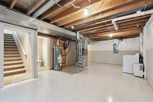 A room with a staircase and a furnace.