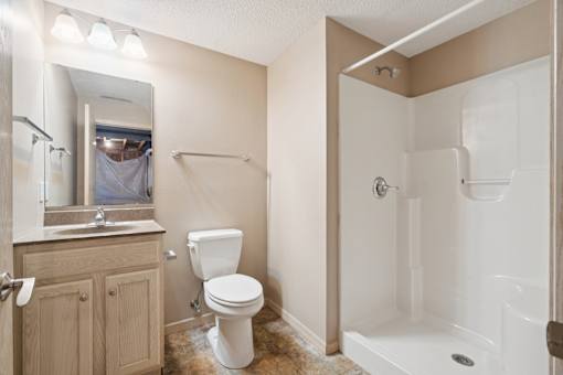 A white toilet sits in a bathroom next to a sink and a bathtub.