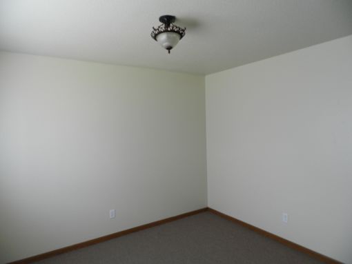 A room with a light fixture on the ceiling and two switches on the wall.
