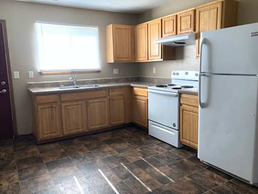 A kitchen with a white refrigerator, white stove, and wooden cabinets.