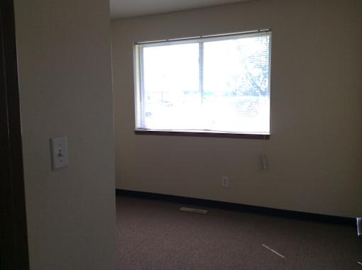 A room with a window and a light switch on the wall.