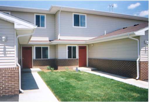 A house with a red door and a green lawn.
