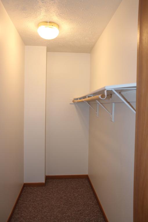 A hallway with a carpeted floor and a light on the ceiling.