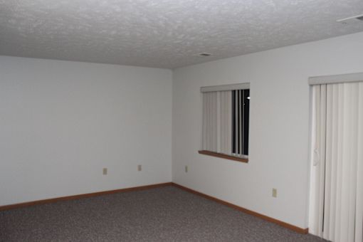 A room with a window and a carpeted floor.