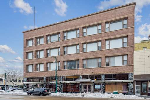 A large brown building with many windows sits on a street corner.