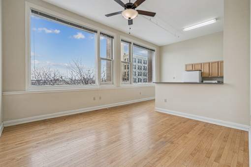 A room with a ceiling fan and wooden flooring.