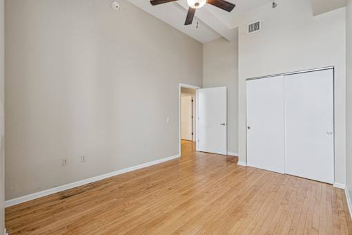 A room with a ceiling fan and two white closet doors.