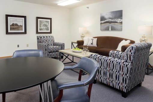 A living room with a brown couch, a round table, and two chairs.