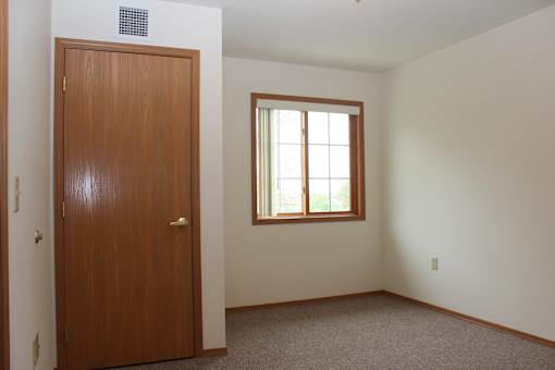 A room with a brown door and a window with white blinds.