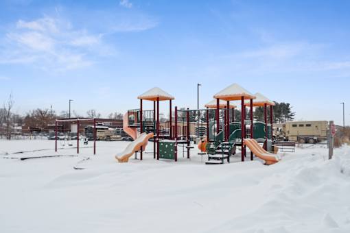 A playground with a yellow slide and a red roofed structure.