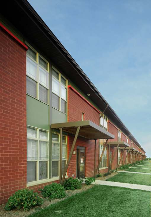 A long row of red brick houses with green trim and white windows.