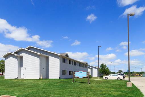 A white building with a blue sign in front of it.