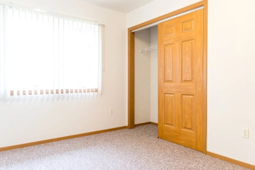 A room with a wooden door and a window with blinds.