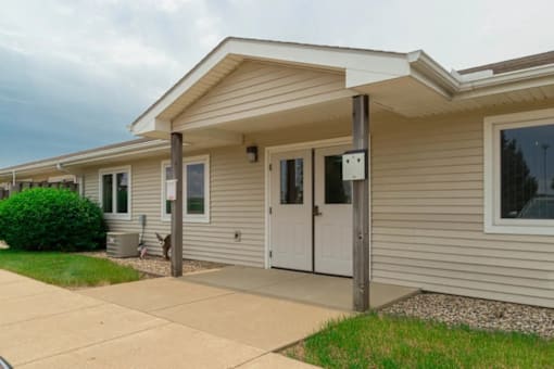A house with a grey siding and a white door.