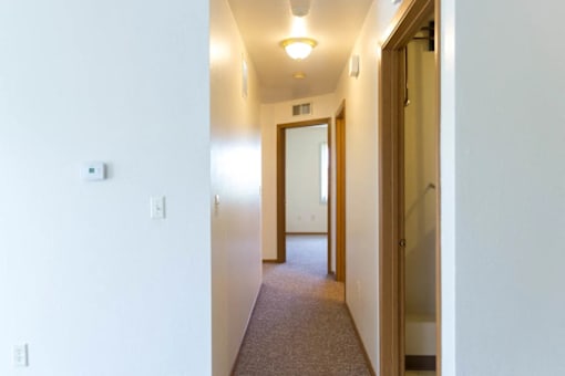 A hallway with a carpeted floor and white walls.