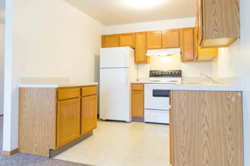 A kitchen with wooden cabinets and a white refrigerator.