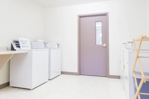 A room with a purple door, white cabinets, and a printer on top of the cabinets.