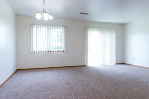 A room with a carpeted floor and a window with blinds.