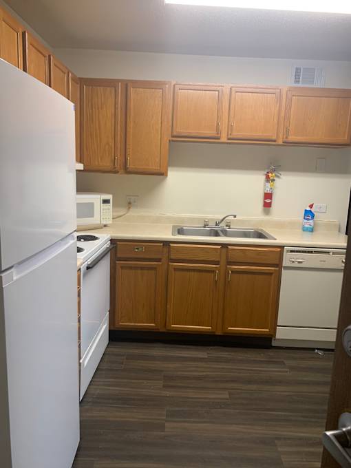 A white fridge in a kitchen with wooden cabinets.