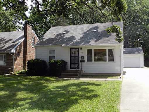 A white house with a black door and a brick chimney.
