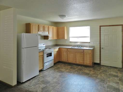 A kitchen with a refrigerator, oven, sink and cabinets.