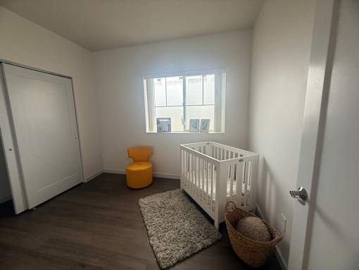 A baby room with a white crib and a yellow ottoman.