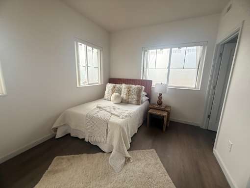 A bedroom with a bed, a small table, and a rug.