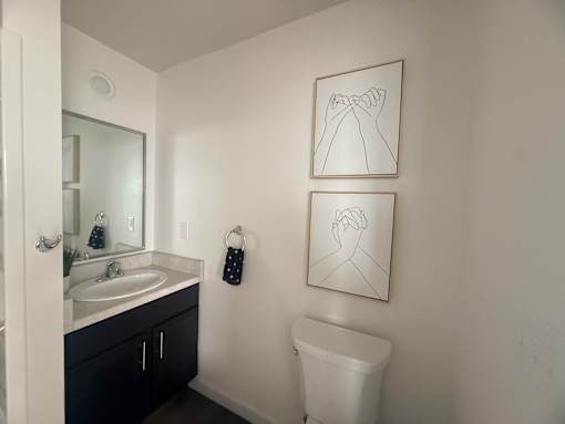 A bathroom with a toilet, sink and two pictures on the wall.