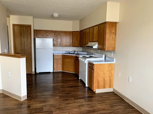 an empty kitchen with white appliances and wooden cabinets