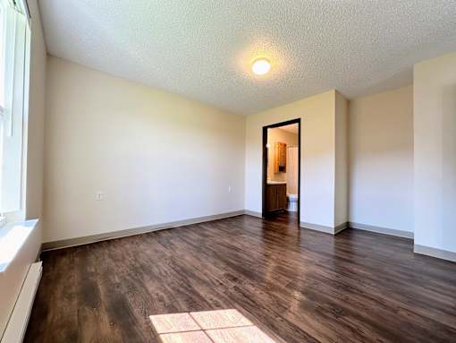 an empty living room with hard wood floors and white walls