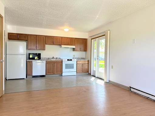 an empty kitchen with white appliances and wooden cabinets