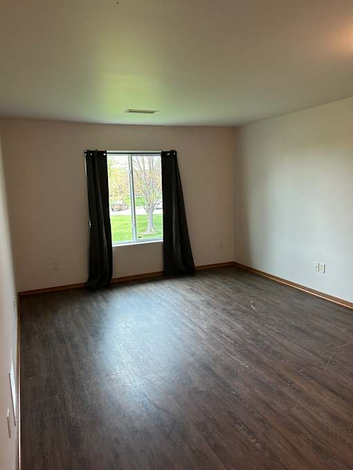 A small window with black blinds is on a white wall.