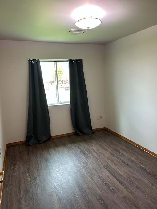 A window with black blinds in a room with a wooden wall.