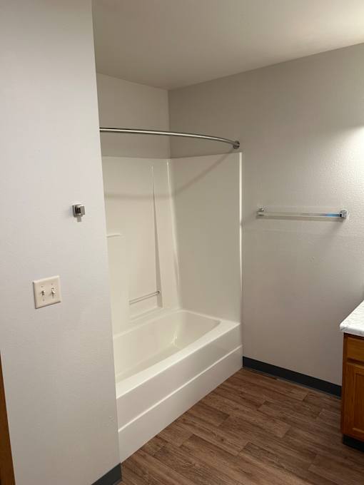 A white bathroom with a shower and a white wall.