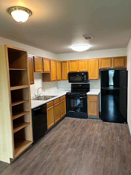 A modern kitchen with wooden drawers and black appliances.