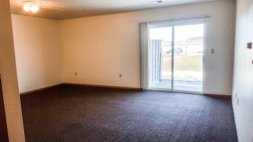 A room with a carpeted floor and a sliding glass door.