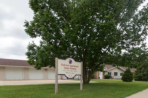 A sign for Parkview Apartments Senior Housing stands in front of a building.