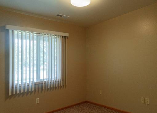 A room with a window covered by white blinds.