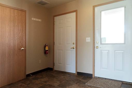 A hallway with a brown door on the left and two white doors on the right.