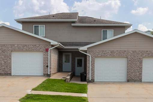 A house with a grey roof and two white garage doors.