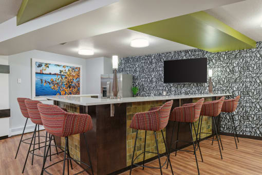 a kitchen with a bar with chairs and a television at Axon Green, Minneapolis, MN, 55416
