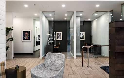 A grey chair sits in a room with a glass wall.