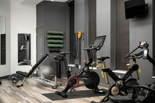 A gym with a variety of exercise equipment including a stationary bike, a rowing machine, and a weight bench.
