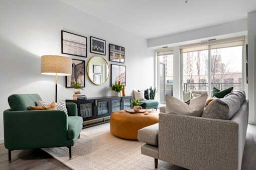 A living room with a green chair, a grey sofa, and a yellow ottoman.